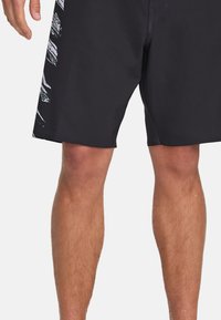 Pantaloni da nuoto neri realizzati in materiale leggero, con un design laterale bianco. I pantaloni hanno una vestibilità classica e una lunghezza sopra il ginocchio.