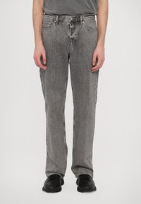 Gray denim jeans with a straight leg design, faded texture, front pockets, and metal hardware, paired with black sneakers.
