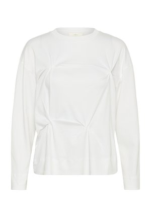 Balta garām piedurknēm ar apaļu kakla izgriezumu krekls ar savāktas auduma detaļām, kas veido neregulāras zvaigžņveida formas priekšpusē un sānos.