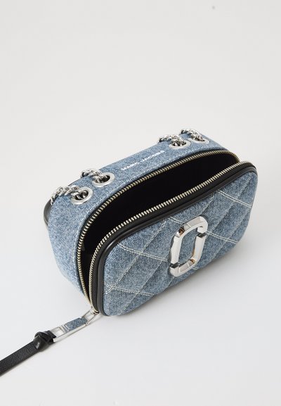 Blue denim crossbody bag with a quilted design, silver hardware, zip closure, and a detachable black strap. Open to show interior lining.