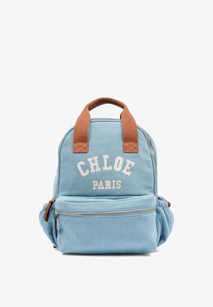 Jasnoniebieski plecak z tkaniny z brązowymi płóciennymi uchwytami, z napisem "CHLOE PARIS" w białym kolorze oraz przednią kieszenią na zamek z jasnobrązowym suwakiem.
