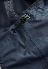 Vodeodolná tkanina námorníckej modrej farby s hladkým povrchom, vybavená čiernym sťahovacím šnúrkou a zarážkou na nastaviteľné upevnenie pri švíku goliera.