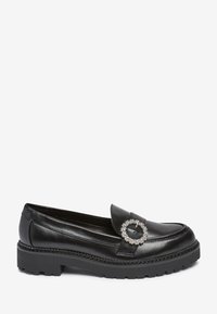 Schwarze Lederloafers mit einer erhöhten Silhouette, ausgestattet mit einem runden silbernen Schnallendetail und dicken Gummisohlen für Traktion.