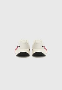 White mesh sneakers with black soles, featuring pink accents on the heel and a textured upper. Rounded toe and cushioned back design.