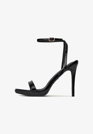 Melnas patentētas ādas augstpapēžu sandales ar vienu siksnu un regulējamu potītes siksnu. Teksturēts zole ar dekoratīviem akcentiem.