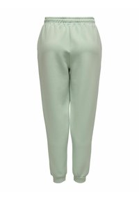 Ljusgröna träningsbyxor gjorda av mjukt material, med resårmidja och smalnande ben med ribbade muddar. Ingen fickor.