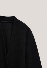 Sort uldblandingsfrakke med sjalskrave, der har en blød tekstur og en struktureret silhuet, skræddersyet til en afslappet pasform.