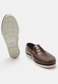 Brown leather loafers with a stitched design, white rubber sole, and a smooth finish. Features a classic slip-on style and side accents.