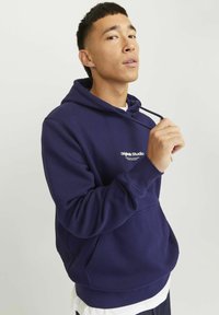 Felpa blu navy con tasca a marsupio frontale, cappuccio con cordino e logo bianco del brand sul petto. Tessuto morbido con una vestibilità comoda.
