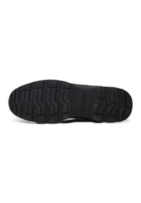 Suela de zapato de goma negra con un diseño de banda para agarre, con surcos en zigzag elevados y el nombre de la marca "WODEN" grabado.