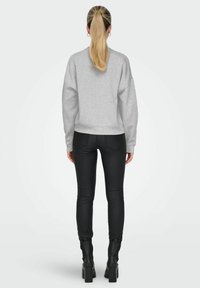 Grijze sweatshirt met hangende schouders, ribbelmanchetten en een ribbelzoom. Gecombineerd met zwarte skinny broeken en stevige zwarte enkellaarsjes.