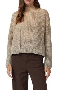 Strickpullover mit hohem Kragen, in einem beigen und hellbraunen Ombre-Muster, lockere Passform und gerippter Textur. Kombiniert mit braunen Hosen.