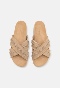 Béžové skládací sandály s kříženými textilními pásky, se strukturovanými kovovými akcenty a měkkou podešví podobnou semiši. Lehký, casual design.