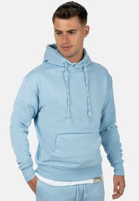 Felpa con cappuccio azzurro chiaro realizzata in tessuto texturizzato. Presenta una tasca frontale, cordini e dettagli del logo sul petto e sull'orlo.