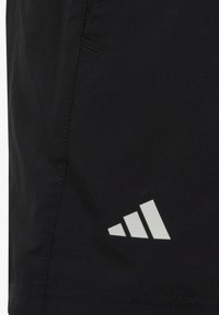 Čierne športové šortky vyrobené z ľahkej tkaniny s hladkou textúrou. Na boku majú biele logo Adidas s tromi pruhmi.