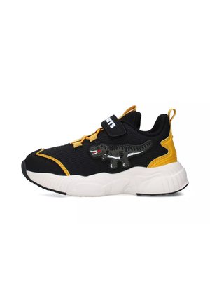Sneaker nera con accenti gialli, tomaia in rete testurizzata, cinturino regolabile e una grafica di un dinosauro sul lato. Suola bianca spessa.
