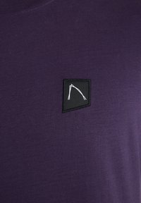 Violet spalvos medvilninis marškinėliai su juodu kvadratiniu pleistru ir baltu abstrakčiu piešiniu. Sudrėkinta tekstūra su apvaliu iškirpimu.