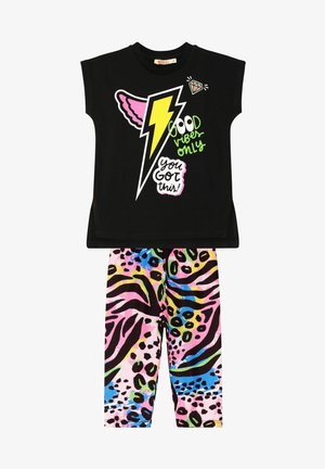 Sort kortærmet skjorte med farverige lyn og tekstgrafik, parret med lyserøde leopardmønstret leggings med grønne og blå accenter.