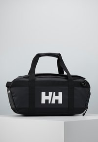 Bolsa de deporte negra hecha de material impermeable, con dos asas de transporte, un bolsillo con cremallera en el lado y un logo blanco prominente en la parte frontal.