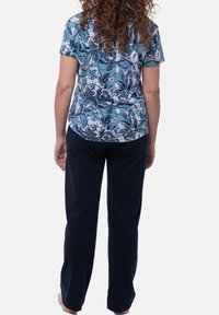 Top a maniche corte con motivo floreale in azzurro chiaro, abbinato a pantaloni elasticizzati blu scuro in vita. Il tessuto sembra morbido e ha una vestibilità rilassata.