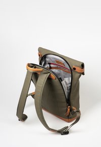 Zaino impermeabile verde oliva con dettagli in pelle color cuoio e spallacci regolabili. Comparto principale con zip, dotato di fodera a scacchi e tasche.