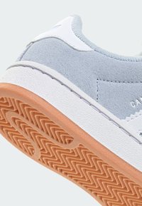 Plava tenisica od antilopa s bijelim teksturiranim srednjim đonom i gumastim potplatom s cik-cak uzorkom. Zaobljeni vrh i podstavljena ovratnik.