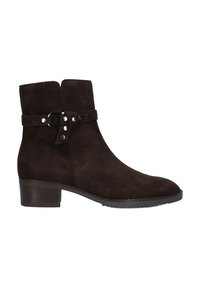 Bottine en daim marron avec un bout arrondi, un petit talon compensé, un détail de boucle sur le côté, et des clous sur une sangle contrastante. Texture lisse dans l'ensemble.