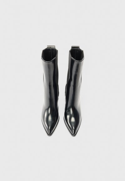 Czarne botki za kostkę z błyszczącej skóry, z czubkiem w kształcie stożka i elastycznymi bocznymi panelami ułatwiającymi zakładanie. Gładka tekstura z minimalnymi detalami.