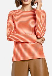 Langarmshirt aus weichem Stoff, mit orange-weißen horizontalen Streifen, rundem Halsausschnitt und lockerer Passform.