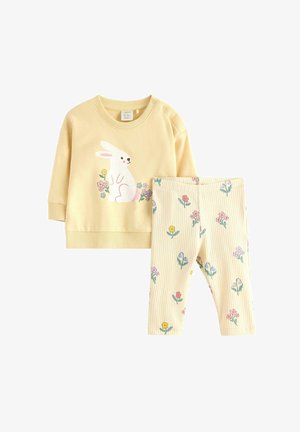 Completo giallo per bambino piccolo con maglietta a maniche lunghe che presenta un coniglio bianco e una stampa floreale, abbinato a leggings a coste con fiori colorati.