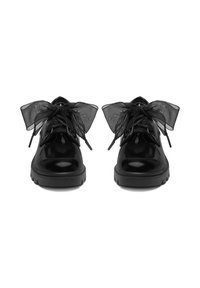 Zapatos de charol negro con punta redondeada y suela gruesa, con grandes lazos de cinta negra transparente como cordones.