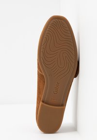 Chaussure en daim marron avec une semelle en caoutchouc texturée ; présente un design courbé et la marque "Gabor" embossée sur la semelle. Taille 4½, fabriquée au Portugal.
