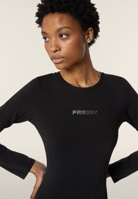 Musta pitkähihaisessa paidassa on sileä kangas ja rintaan ommeltu kristallikirjailtu "FREDDY"-logo. Tiukka malli, jossa on pyöreä kaula-aukko.