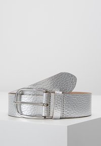 Ceinture en cuir argenté avec une finition texturée, dotée d'une boucle métallique et d'un bord lisse cousu. La ceinture s'effile vers une extrémité arrondie.