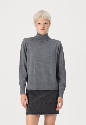 Suéter gris de punto suave, con mangas largas y un corte relajado, combinado con una falda negra que presenta pequeños detalles de cortes.