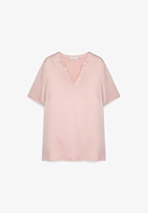 Jemně růžová krátký rukáv halenka se širokým výstřihem do V a volnějším střihem, zobrazena na bílém pozadí.