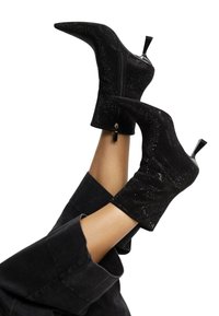 Čierne členkové topánky s špicatou špičkou, vyrobené z textúrovaného materiálu, so zipsom a úzkym vysokým ihlovým podpätkom.