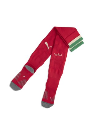 Calzettoni sportivi rossi con talloni e punte grigie, polsini a righe verdi e bianche, logo Puma e scritta araba sulla zona dello stinco.