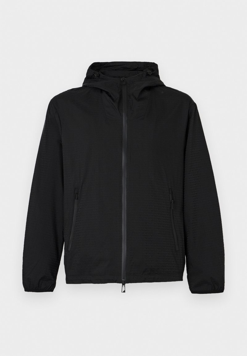 Giacca leggera nera con cappuccio, cerniera frontale e tasche laterali con zip, polsini elastici e coulisse regolabili sul cappuccio.