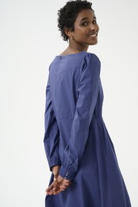 Vestido azul marino con mangas largas, detalles de hombros abullonados, un escote redondo y acentos de puño abotonados. Tejido suave con un diseño fluido.