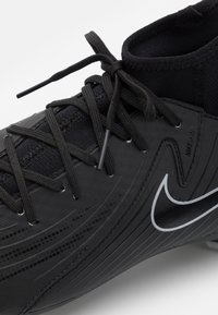 Zbliżenie czarnego korka do piłki nożnej Nike z zawiązanymi sznurowadłami i białym logo Swoosh na teksturowanej syntetycznej cholewce.