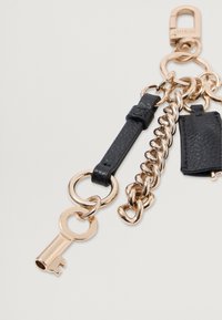 Ključna veriga z črnim usnjenim trakom, zlatim kovinskim verigo in ključnim akcentom. Vključuje majhno črno teksturirano torbico.