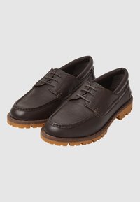 Scarpe in pelle marrone con punta tonda e cuciture decorative, caratterizzate da una parte superiore texturizzata e una suola in gomma con tacche per una migliore aderenza.