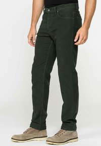 Pantaloni di cotone verdi con un design slim fit, stile a cinque tasche e una texture sottile. Abbinati a scarpe in suede beige.