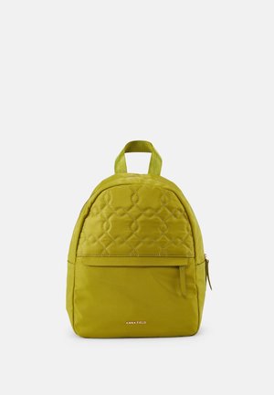 Lille olivengrøn quiltet rygsæk med lynlåslomme foran, stofhåndtag og "ANNA FIELD" logo på nedre front.