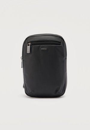 Kompakt svart skulderveske med glidelåslomme foran, sølvfarget BOSS-logo og glatt, minimalistisk design mot en ensfarget hvit bakgrunn.