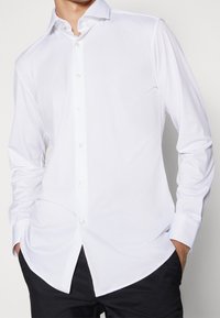 Witte long-sleeve shirt met een button-down kraag, met een gladde textuur en een rechte snit, aangevuld met parelachtige knopen.