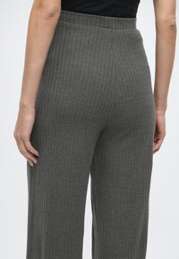 Harmaat ribbineulokset, joissa leveät lahkeet ja joustava vyötärönauha. Kankaan pinta on pehmeä, ja siinä on koko matkalta pystysuora ribbineulosdetaili.