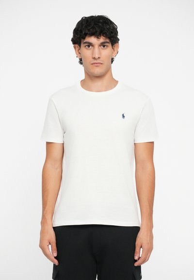 T-shirt branca de algodão com decote redondo, apresentando um pequeno logótipo azul-marinho no lado esquerdo do peito. Mangas curtas e um design de corte regular.