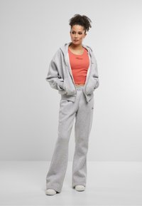 Sivá mikina a tepláky s krátkym korálovým tielkom. Mäkká látka, voľný strih a diskrétny logo detail na hrudi.